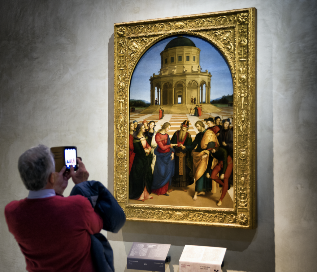 A man taking a photo of a Raphael painting